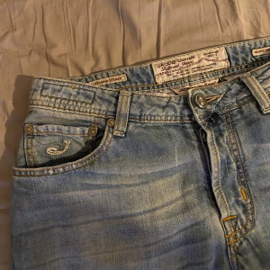  Jacob Cohen jeans - Säljer ett par klassiska ljusblå jeans från Jacob Cohen med raka ben och normal passform. Jeansen har fem fickor, broderad J-logga på fickan och snygga detaljer för en avslappnad look.