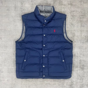 Ralph Lauren Medium Blå/Grå vändbar väst - 📊Färg: Ena sidan är blå och andra är grå  📏Storlek: Medium (M)  Storleken passar som en Medium och hade eventualt passat någon som bär L   ♻️ Jätte bra skick, knappast använd   📲 Tveka inte att skriva om du har några frågor! 