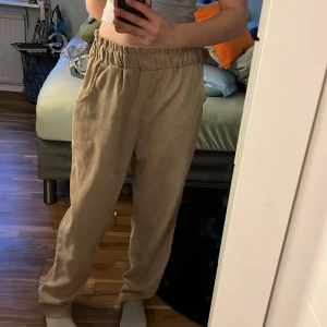 Beiga byxor med resårmidja - Säljer ett par beiga byxor med avslappnad passform och resår i midjan. Byxorna har raka ben och sidfickor, perfekta för en chill och stilren look. Lätta och luftiga, passar bra till varmare dagar. Dem är inte använda förutom bilden jag tog nu. Är villig att sänka priset 