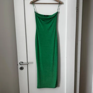 Axelbandslös grön långklänning - Säljer en snygg grön långklänning utan axelband. Klänningen har en smal passform och är tillverkad i ett mjukt, stretchigt material som ger en elegant siluett. Perfekt för dig som vill sticka ut med färg!