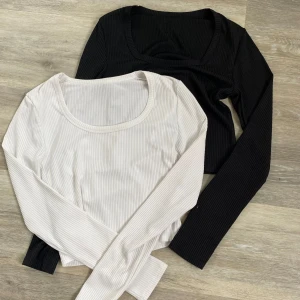 Ribbade långärmade toppar  - Två långärmade ribbade toppar i storlek S. En är svart och en är vit, båda med rund halsringning och figurnära passform. Tillverkade i 100% polyester, perfekta för att matcha med jeans eller kjol.