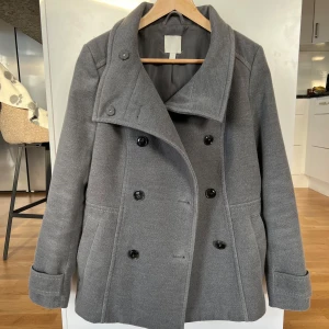 Kort kappa - Grå vårjacka från H&M. Lite figursydd och knappt använd då den är för stor för mig