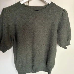 Grön stickad tröja - Säljer en mysig grön stickad tröja med korta ärmar. Perfekt för kyligare dagar och enkel att matcha med olika outfits.