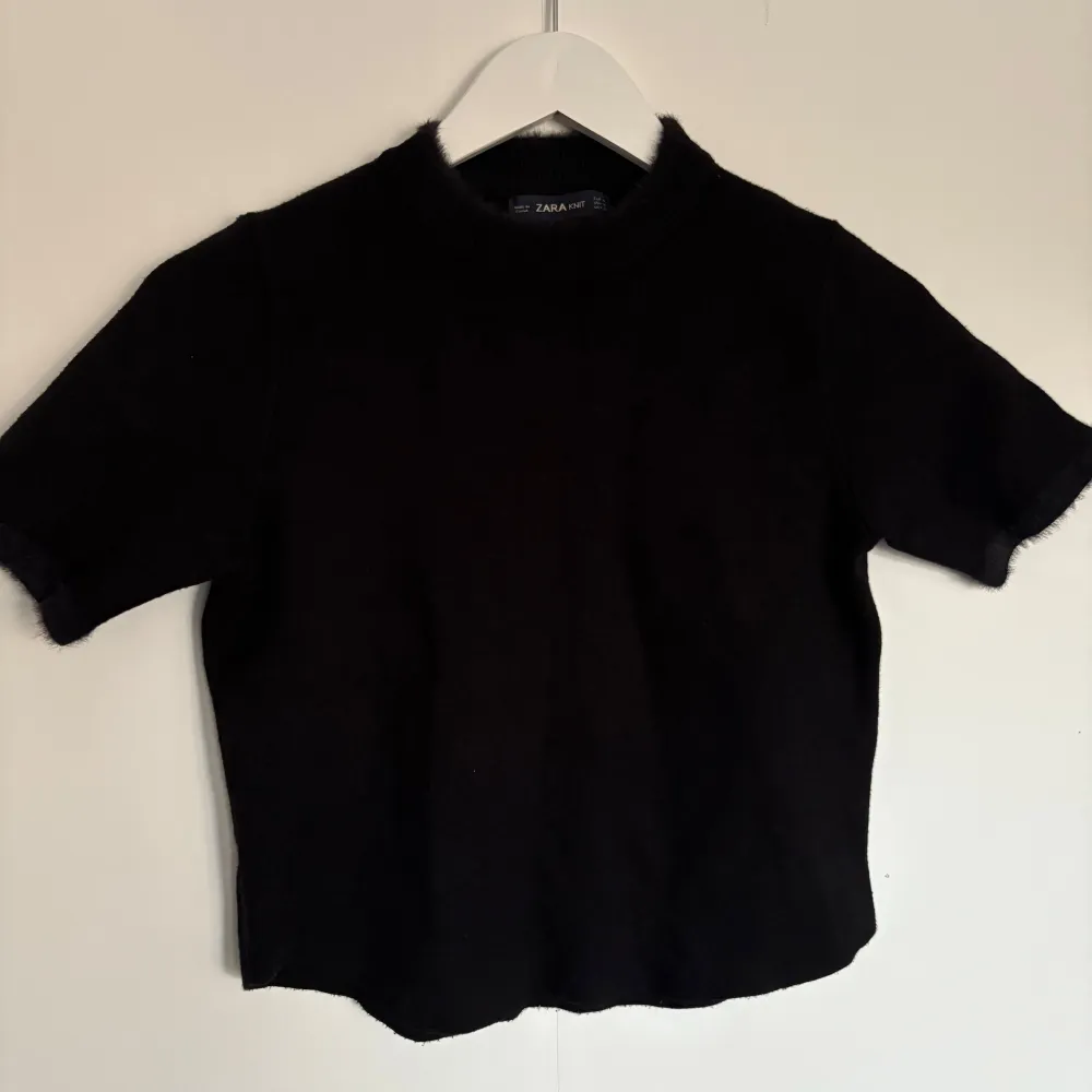 Säljer en stilren svart stickad topp från Zara. Den har korta ärmar och en rund halsringning. Perfekt för en minimalistisk look. Passar bra till både jeans och kjol. Tröjan är i storlek M men passar mer som xs . Neuleet.