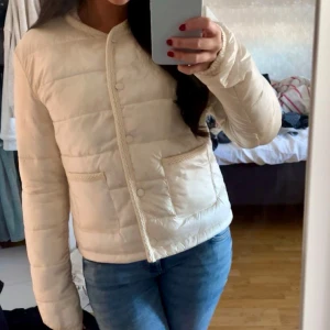 Beige dunjacka från Gina Tricot - Säljer en snygg beige dunjacka från Gina Tricot. Jackan har en quiltad design med knappar framtill och två praktiska fickor. Perfekt för kyligare dagar med sin stilrena look och bekväma passform. Helt ny eftersom jag inte hann returnera. Slutsåld på hemsidan