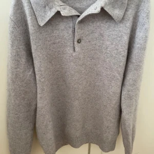 Grå 100% kashmirtröja från A Day's March - Säljer en stilren och mjuk grå kashmirtröja från A Day's March. Tröjan har en klassisk krage med knappar och långa ärmar. Tröjan är otroligt skön och stilren. Nypris är 1850kr. 