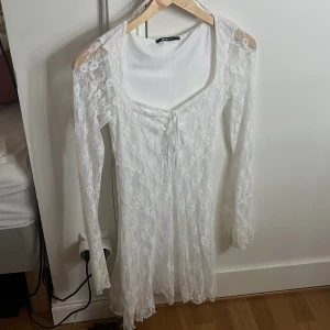 Vit spetsklänning från Gina - Säljer en elegant vit spetsklänning från Gina med långa ärmar och en v-ringad design. Klänningen har en fin spetsdetalj. 💞
