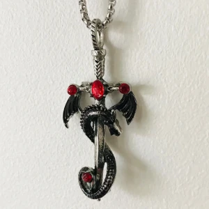 Halsband med drakdesign och röda stenar - Unikt halsband med en drakdesign som slingrar sig runt ett svärd. Smycket är i silverfärg med detaljer i svart och har flera röda stenar som ger en mystisk känsla. Perfekt för den som gillar fantasy och drakar.