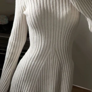 Beige ribbad klänning - Snygg beige ribbad klänning med långärmad design. Perfekt för en stilren look med sin figurnära passform och mjuka material. Enkelt att matcha med olika accessoarer för en personlig touch. Använt fåtal gånger, från H&M.