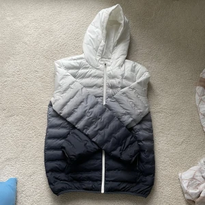 Vårjacka I Pier one - Säljer en snygg pufferjacka i blåt och vitt med huva och en cool ombre-effekt från ljus till mörk. Perfekt för vår dagar när du vill hålla stilen. 