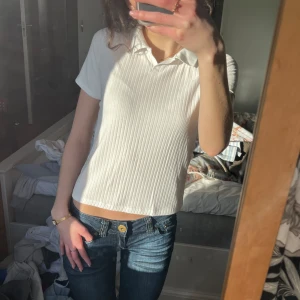 Vit ribbad polotopp - Säljer en stilren vit ribbad polotopp med korta ärmar. De är barnstolek men passar xxs - xs