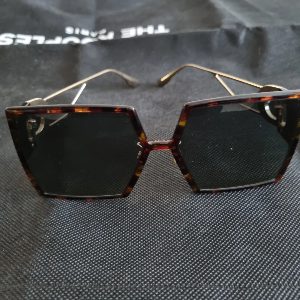 Snygga oversized solglasögon med fyrkantig form och sköldpaddsmönstrad ram. Glasögonen har mörka linser och tunna guldfärgade skalmar med en dekorativ detalj vid gångjärnen. Äkta Christian Dior. Inköpta i Stockholm . Asusteet.