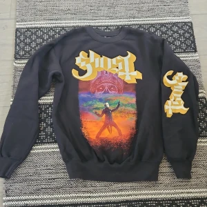 Ghost Svart sweatshirt från Fruit of the Loom - Cool svart sweatshirt från Fruit of the Loom med ett färgglatt tryck på framsidan och text i gult. Perfekt för dig som vill sticka ut med en unik stil. Tröjan har långa ärmar och en klassisk rund halsringning. Strl S