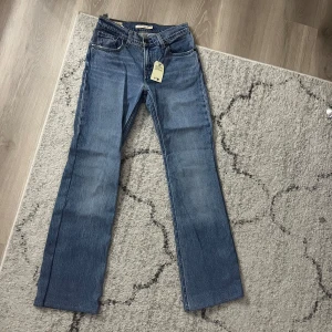 Blå jeans från Levi's - Snygga blå jeans från Levi's med en klassisk design. De har en midwaist passform och en flare stil som ger en trendig look. Perfekta för att matcha med olika toppar och skor.