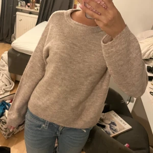 Beige stickad tröja - Mysig beige stickad tröja med rund hals och långa ärmar. Perfekt för kyligare dagar och enkel att matcha med jeans eller kjol. En klassisk och tidlös design som passar i alla garderober.