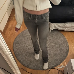 Grå stretchiga straight fit jeans - Säljer dessa jättesnygga lågmidjade jeans i straight fit modell då de börjar bli för små på mig. De har stretchigt material och är i en jättefin grå färg😍😍Waist 24 Length 34. (Det som ser ut som en fläck på bilden är en skugga av fjärilen på spegeln)