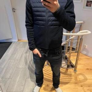 Svart quiltad jacka från Duke - Säljer en stilren svart quiltad jacka från Duke. Jackan har en dragkedja framtill och långa ärmar. Perfekt för kyligare dagar med sin lätta och bekväma design.