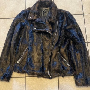 Svart pälsjacka från Zara - Säljer en snygg svart pälsjacka från Zara med dragkedja och coola detaljer. Jackan har en modern look med långa ärmar och är perfekt för att ge din outfit en extra edge. Passar perfekt för kyligare dagar och kvällar.