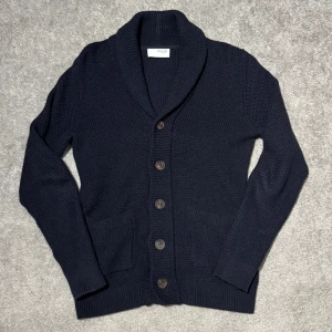 Selected Homme Stickad Kofta - Säljer en oanvänd shawl neck stickad kofta i marinblå färg frän selected Homme. Köpt för: 689kr. Storlek S passar S/M alltsà mellan 178-188 drygt.