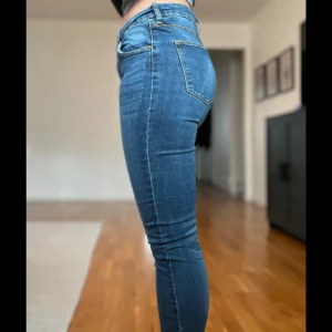 Blå skinny jeans - Snygga blå skinny jeans med hög midja och klassisk femficksdesign. Perfekta för en stilren look. De har en dragkedja och knapp framtill.