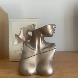 Parfymflaska i form av en torso - Unik parfymflaska i form av en stiliserad torso i metallisk färg. Flaskan har en elegant och konstnärlig design som påminner om en skulptur. Perfekt som en dekorativ detalj i hemmet eller som en speciell present.