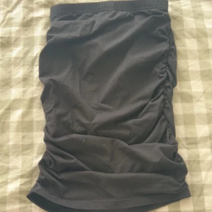 Svart kjol med rynkade detaljer - Snygg svart kjol med rynkade detaljer på sidorna. Perfekt för en stilren look. Kjolen har en elastisk midja för extra komfort.