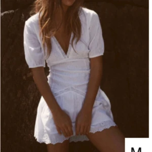 Vit klänning med spetsdetaljer - Säljer en söt vit klänning med v-ringning och spetsdetaljer som är perfekt för student och likande. Klänningen har korta ärmar och en fin broderad design. Perfekt för sommarens varma dagar! Klänningen har en liten fläck vid kragen som man ser på sista bilden men det är inget man tänker på!