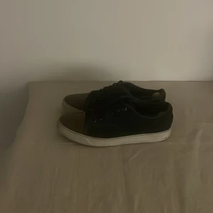 Marinblåa sneakers från Lanvin - Snygga marinblåa sneakers från Lanvin med vita sulor och bruna detaljer på tån. Perfekta för en stilren look. Skorna har snörning och en klassisk design som passar till många olika outfits. Nypris 590$ ≈ 6000kr mitt pris 1599kr. Storlek 9 vilket är 42-43