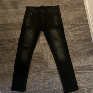 Svarta jeans från DSQUARED2 - Snygga svarta jeans från DSQUARED2 med en cool, sliten look. De har en klassisk femficksdesign och en diskret logga på baksidan. Perfekta för en stilren och modern outfit.