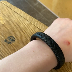 Svart flätat armband med metallspänne. - Snyggt svart armband i flätat skinn med ett stilrent metallspänne. Perfekt accessoar för en modern look. One size