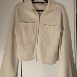 Beige jacka med dragkedja - Snygg beige jacka med dragkedja och två stora fickor framtill. 