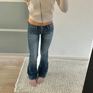 Blå bootcut jeans - Snygga blå bootcut jeans med låg midja. Perfekta för en avslappnad stil. Klassisk design med fem fickor och knappgylf.