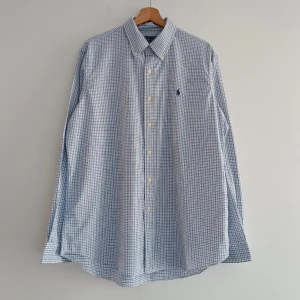 Ralph lauren skjorta - Snygg blårutig skjorta från Ralph Lauren med broderad logga på bröstet. Skjortan har långa ärmar och knappar framtill. Perfekt för en stilren look.