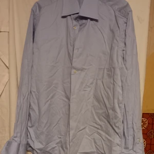 Ljusblå skjorta från Batistini.  - Säljer en stilren ljusblå skjorta från Batistini Top Line. Skjortan har långa ärmar och klassiska knappar framtill. Perfekt för en elegant look. 