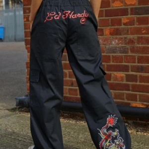 Svarta byxor med drakbroderi från Ed Hardy - Coola svarta byxor från Ed Hardy med ett färgglatt drakbroderi på benet. Byxorna har en loose passform och är dekorerade med Ed Hardy-loggan 😝😝