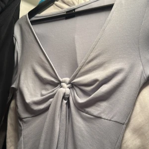 Ljusblå tröja med knut från Gina Tricot - Snygg ljusblå tröja från Gina Tricot med en elegant knytdetalj framtill. Tröjan har en v-ringad design och är perfekt för en stilren look. Materialet känns mjukt och bekvämt mot huden.