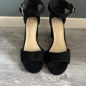 Svarta klackskor - Snygga svarta klackskor från Depeche med ca7-8 cm klack och justerbart spänne runt. Används endast en gång. Perfekta för att lyfta din outfit med stil. Storlek 37. 