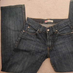 Levi's 506 Standard Jeans - Klassiska Levi's 506 Standard jeans i blå denim. De har en normal passform med dragkedja och knappstängning. Perfekta för en avslappnad stil med fem fickor och slitstarka sömmar. Knappt använda, Innerbenslängd 77cm,                        Midjemått rakt över 39cm.