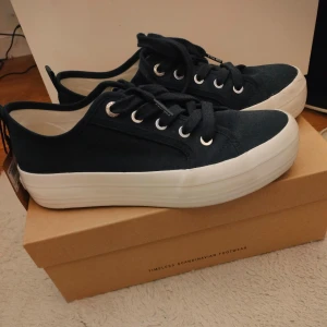 Marinblå sneakers från Stockholm Design Group  - Snygga marinblå sneakers från Stockholm Design Group med vit sula och snörning. Tillverkade i 100% ekologisk bomull för en hållbar stil. Perfekta för en avslappnad look. Endast använda en gång så de är lite smutsiga på sulan och inuti men går säkert att tvätta bort, storlek 39.