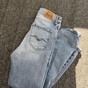 Ljusblå jeans från Replay - Snygga ljusblå jeans från Replay med klassisk femficksdesign och en bekväm passform. Jeansen har en diskret tvättad look och en läderpatch med Replay-logga på baksidan. Perfekta för en avslappnad stil. Knappt använda och är i storleken 14A H158 Cm. Hör av dig vid frågor eller funderingar ✅.