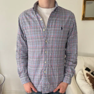Ralph Lauren skjorta  - Ralph lauren skjorta i ett snyggt blått/vitt/rött mönster. Storlek S och i mycket fint skick. Nypris 1599kr kr, köp för endast 399kr. Modellen på bilden är 176cm.