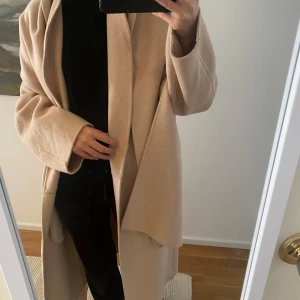 Beige kappa - Säljer en stilren beige kappa med lång ärm och en elegant, enkel design. Perfekt för att hålla sig varm och snygg under kyligare dagar. Passar till många olika outfits och tillfällen.