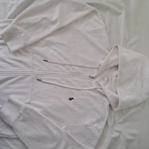 Vit hoodie från Polo Ralph Lauren - Säljer en stilren vit hoodie/zip från Polo Ralph Lauren med dragkedja och det klassiska logotypbroderiet på bröstet. Perfekt för en avslappnad look. Den har långa ärmar och en bekväm passform. Priset går att diskuteras för 700 kr