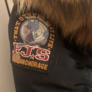 Svart/blå parkajacka från Parajumper - Säljer en svart parkajacka från Parajumpers med pälsdetaljer på huvan. Perfekt för vintern med sitt varma material. Hålet går att fixa rätt enkelt, därför är priset så billigt. Går att diskutera priset