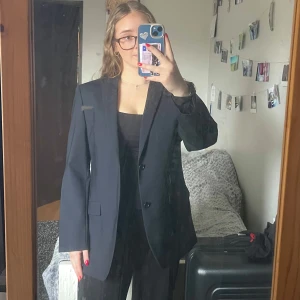 Kavaj - Snygg svart kavaj med klassisk design och två knappar framtill. Perfekt för en stilren look. Passar bra till både byxor och kjol. Oklart vilken storlek det är men den sitter som M/L. Kavajen är väldigt mörk blå (i princip svart) i det exkusiva märket Riley 