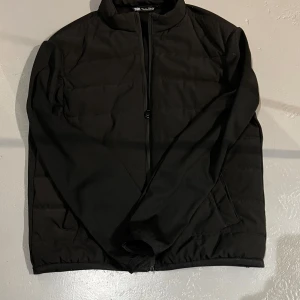 Svart jacka från Zara - Säljer en stilren svart jacka från Zara. Jackan har en dragkedja framtill och är långärmad. Perfekt för en minimalistisk look.