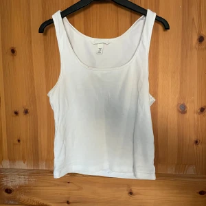 Vit linnetopp från H&M - Säljer en enkel och stilren vit linnetopp från H&M. Perfekt för varma dagar eller som lager under andra plagg. Toppen har en klassisk design med breda axelband och rund halsringning.