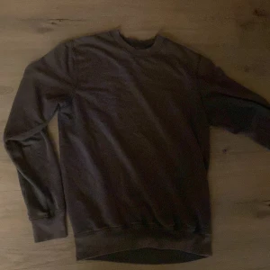 Grå tröja från DNMD - Säljer en stilren grå tröja från DNMD. Tröjan har en klassisk rund hals och långa ärmar, perfekt för en avslappnad look. Materialet känns mjukt och bekvämt mot huden. Passar bra till både jeans och chinos.