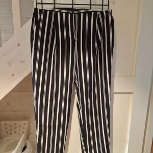 Svartvitrandiga byxor från Monki - Snygga svartvitrandiga byxor från Monki i storlek 38. Byxorna har en bekväm passform med elastisk midja och raka ben. 