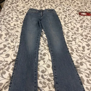 Blå bootcut jeans - Säljer ett par klassiska blå bootcut jeans med normal passform. Jeansen har dragkedja och knapp framtill samt fickor fram. Perfekta för dig som gillar en tidlös stil.